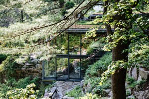 a modernist glass house set in a mountain forestoverlooking a quarry with a grass roof