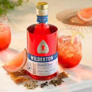 A bottle of Wilderton non-alcoholic spirit on a counter with botanicals