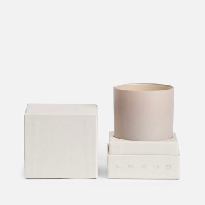 A ceramic candle shown in a box with the top of the box next to it
