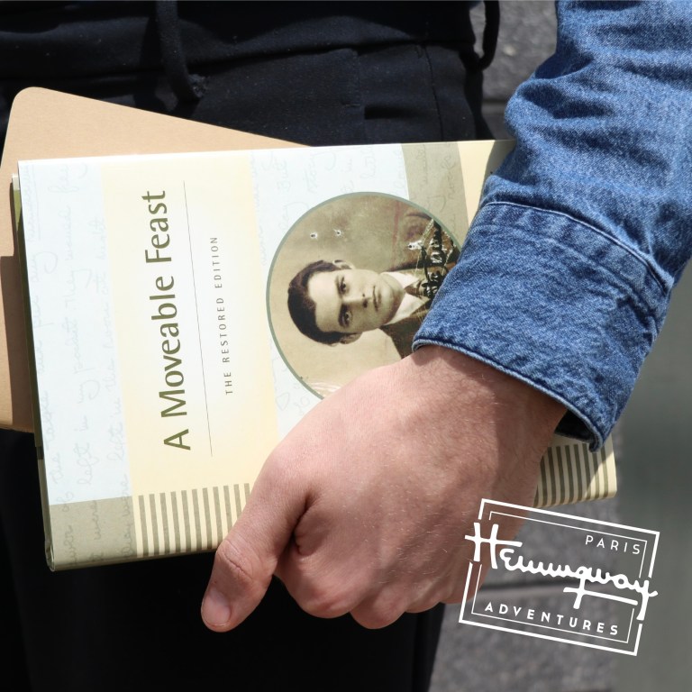 A man holds a book by Ernest Hemingway