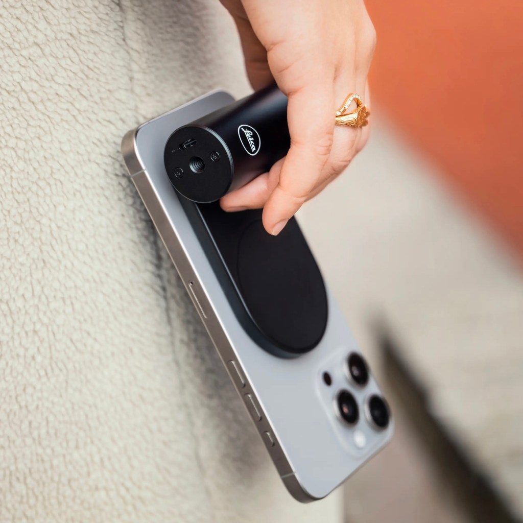 A woman holds an iPhone with Leica's LUX grip attached
