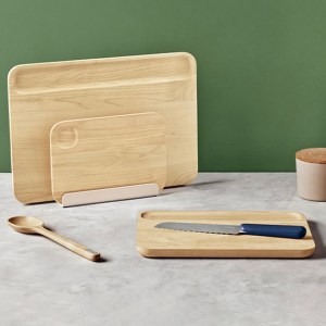 Three different sized wood cutting boards on a counter with a wooden spoon and knife