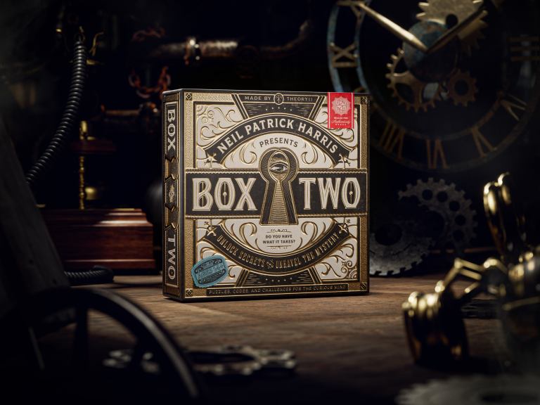 brown and gold game box on a wood floor surrounded by clocks and gears