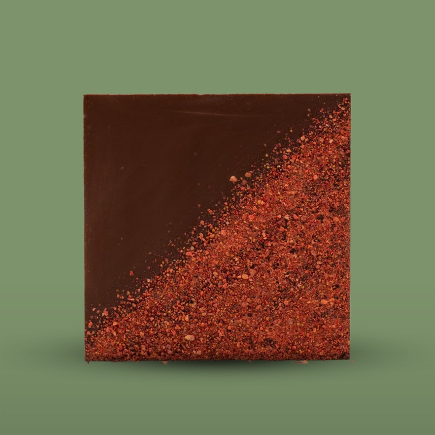 A square chocolate bar with half of the surface covered in dehydrated strawberry dust