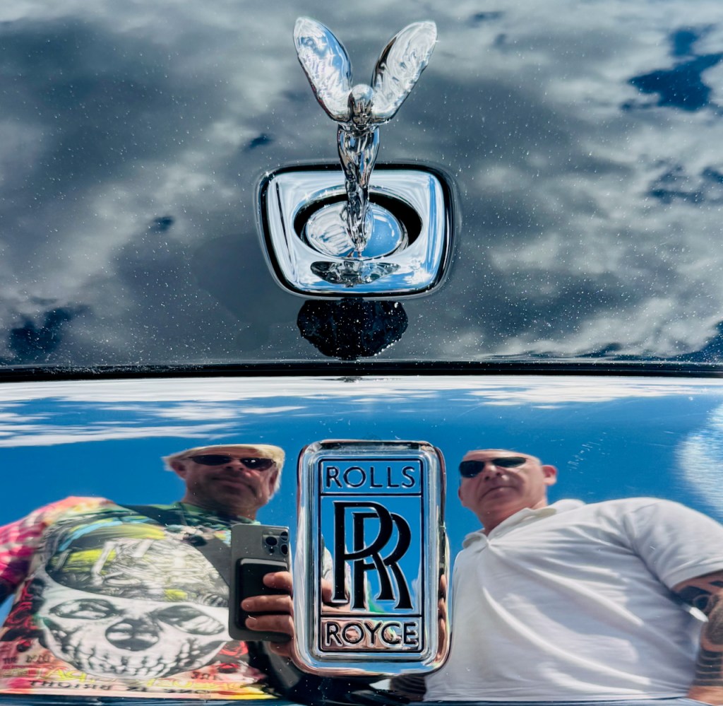 Rolls Royce badge and Spirit of Ectasy hood ornament with Josh Rubin and Evan Orensten reflected in chrome