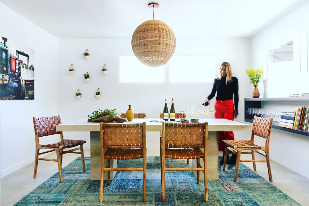 brightly lit room with table and woman pouring white wine