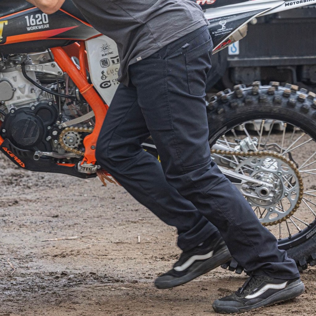 A man pushing a motorcycle wearing a pair of Foundation pants