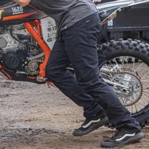 A man pushing a motorcycle wearing a pair of Foundation pants