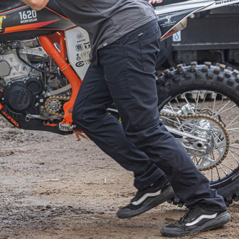 A man pushing a motorcycle wearing a pair of Foundation pants