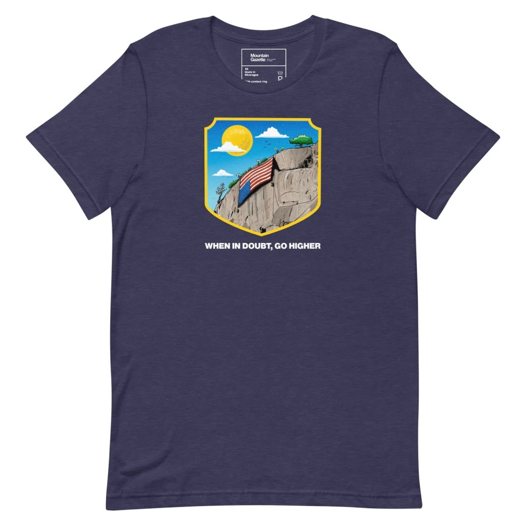 A blue t-shirt featuring an illustration of a mountain with an upside down flag and the mottow "When in Doubt, Go Higher"