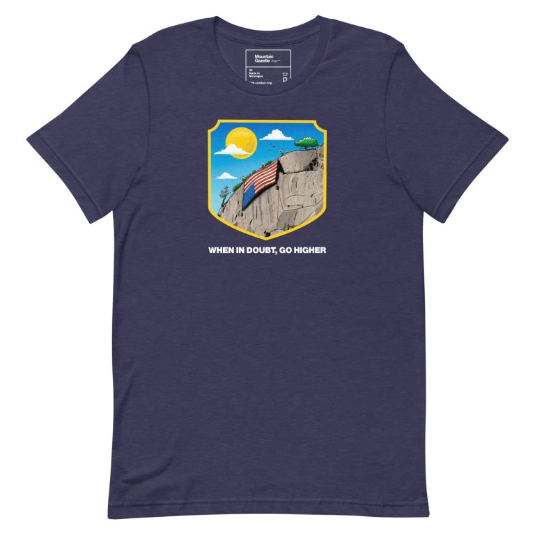 A blue t-shirt featuring an illustration of a mountain with an upside down flag and the mottow "When in Doubt, Go Higher"