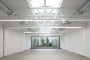 a warehouse space with a skylight through the center of the roof shows what the Convey flexible display and social space, designed by Simple Flair, offers at Milan's 2025 Design Week