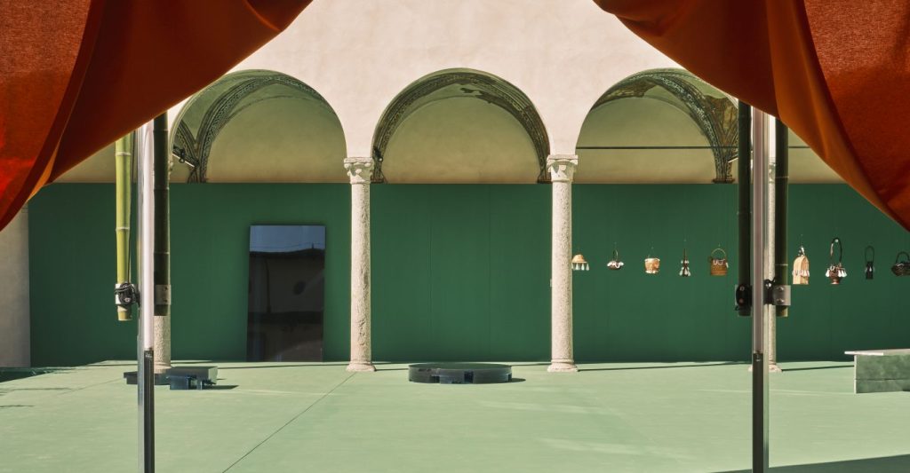 A view of an arched courtyard with several Gucci bags hanging from wires.