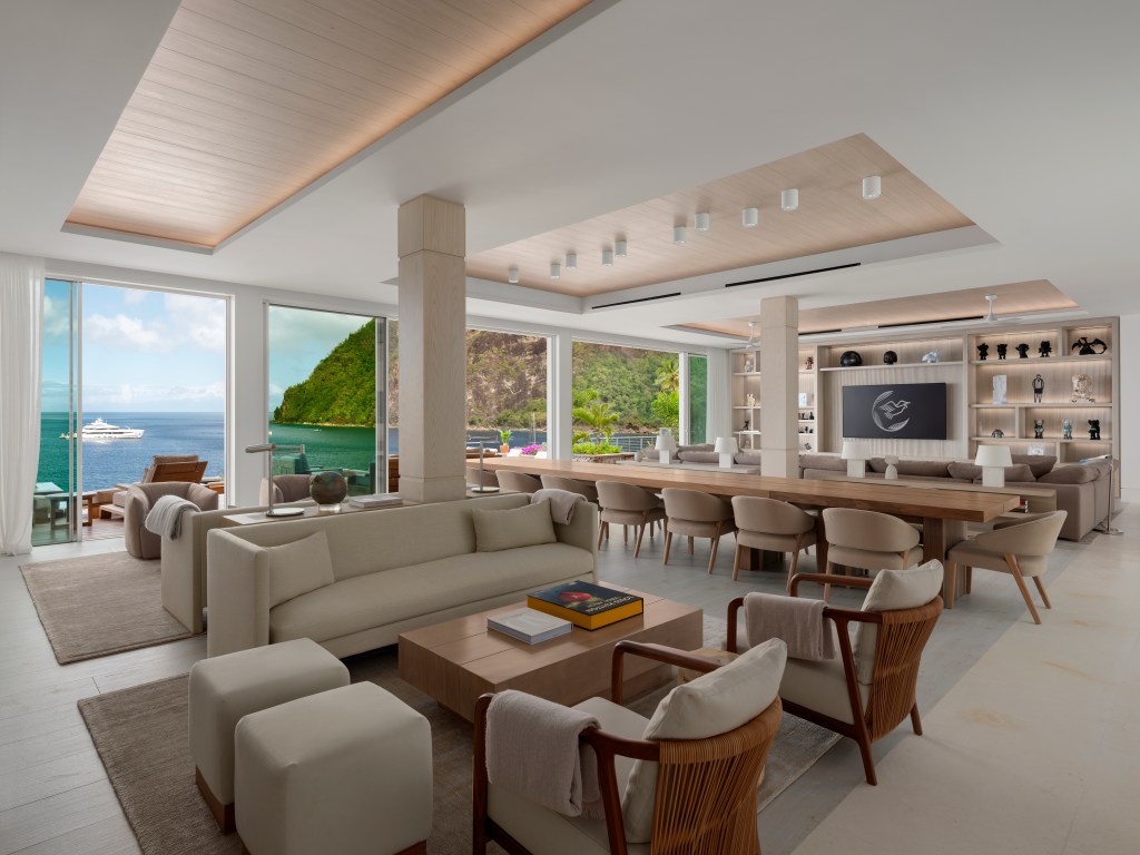 large living room with ocean view, beige furniture, sculptures, books and paintings