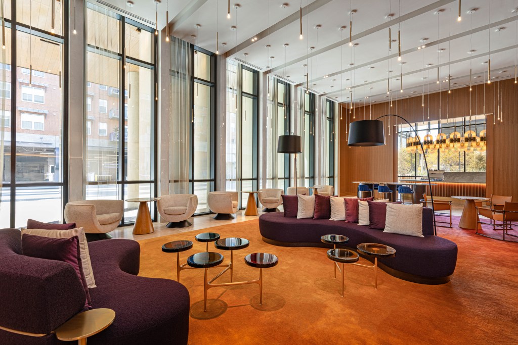 The W Austin's newly designed Living ROom space with brighter colors, full height glass windows, and a view of the new coffee space