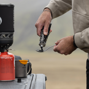 A man squeezes a tube of No Normal Coffee onto a spoon outdoors