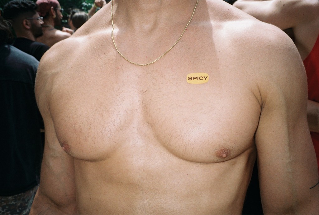 a bare-chested man with a sticker that says "spicy"