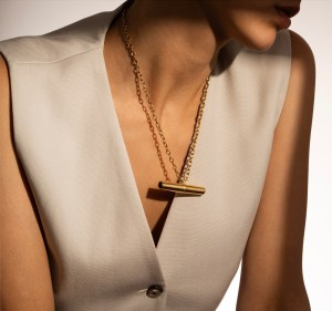 A woman wears a gold chain necklace with a small gold vibrator