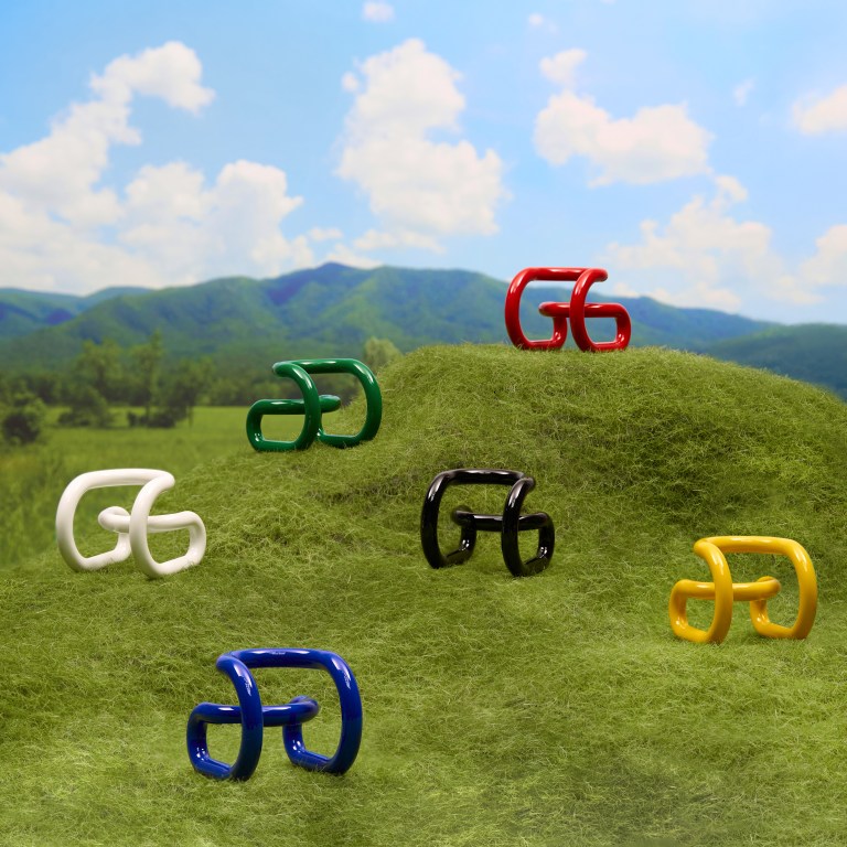 Nik Bentel's Loopy Chair placed on a hill in white, green, red, black, blue and yellow