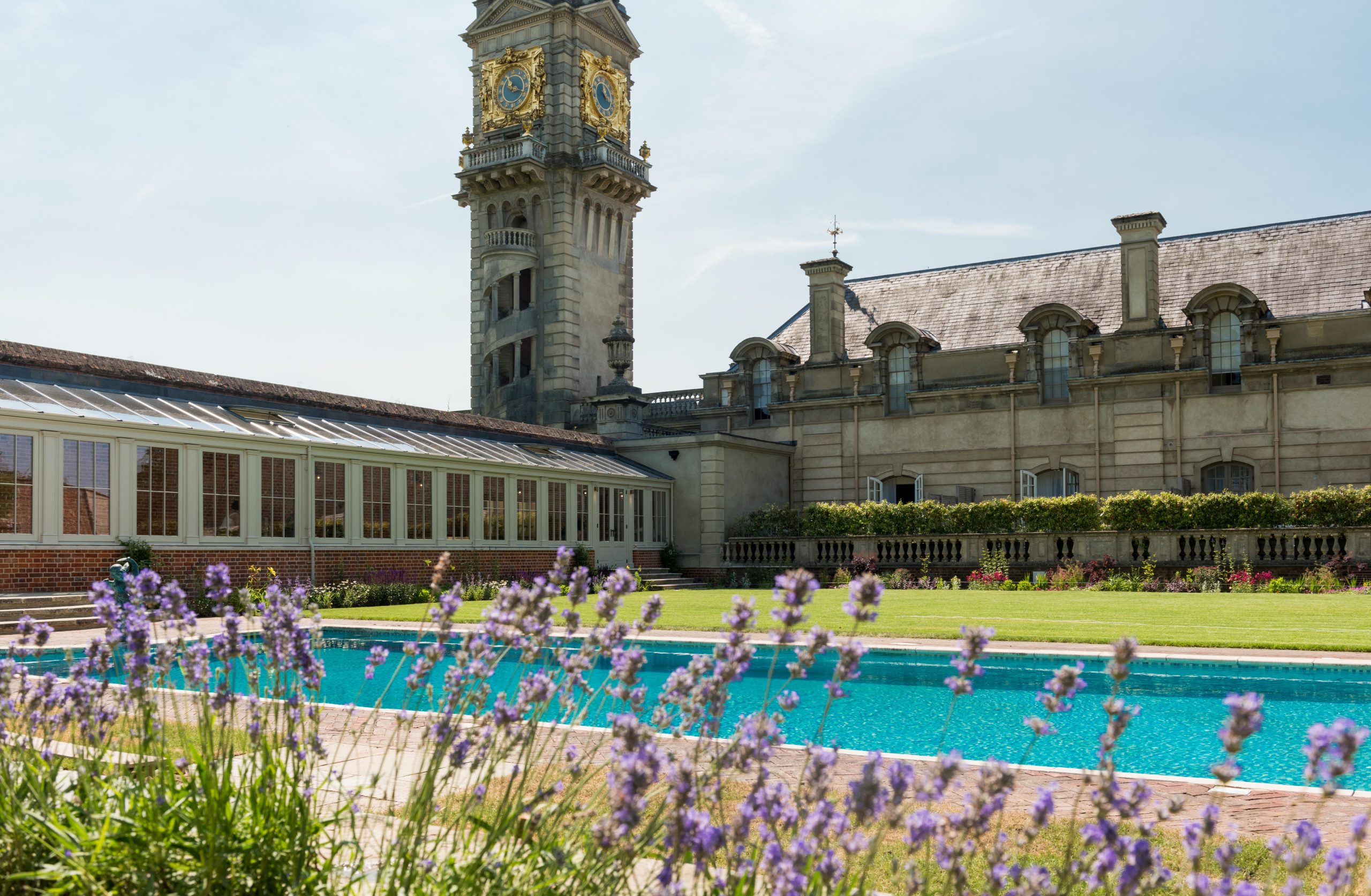 A pool with lavender flowers in the foreground and Cliveden House in the background.