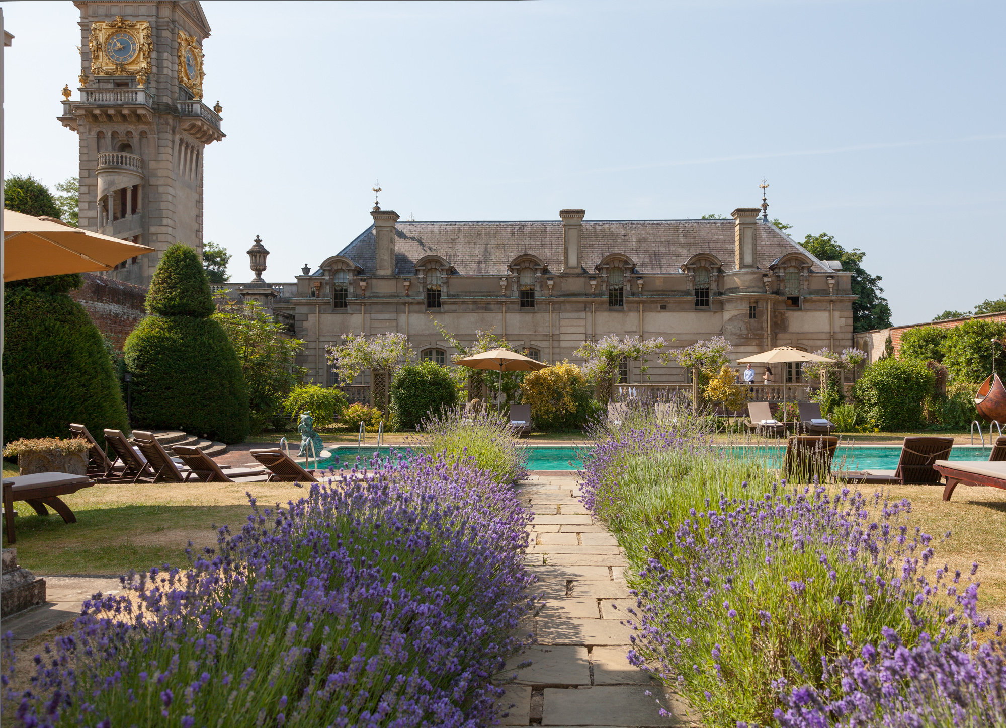 A lavender path leading to a swimming pool and the Cliveden House.