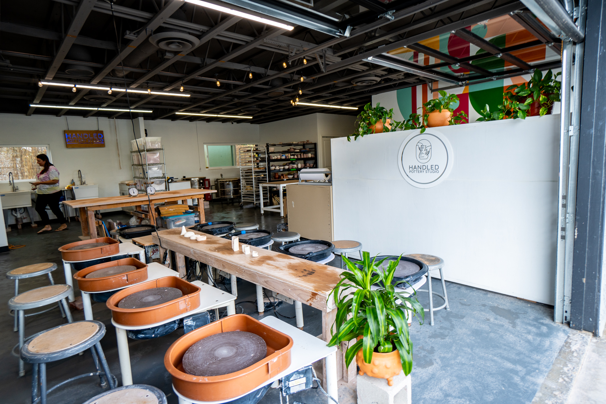 a room of several pottery wheels and a green plant in the foreground