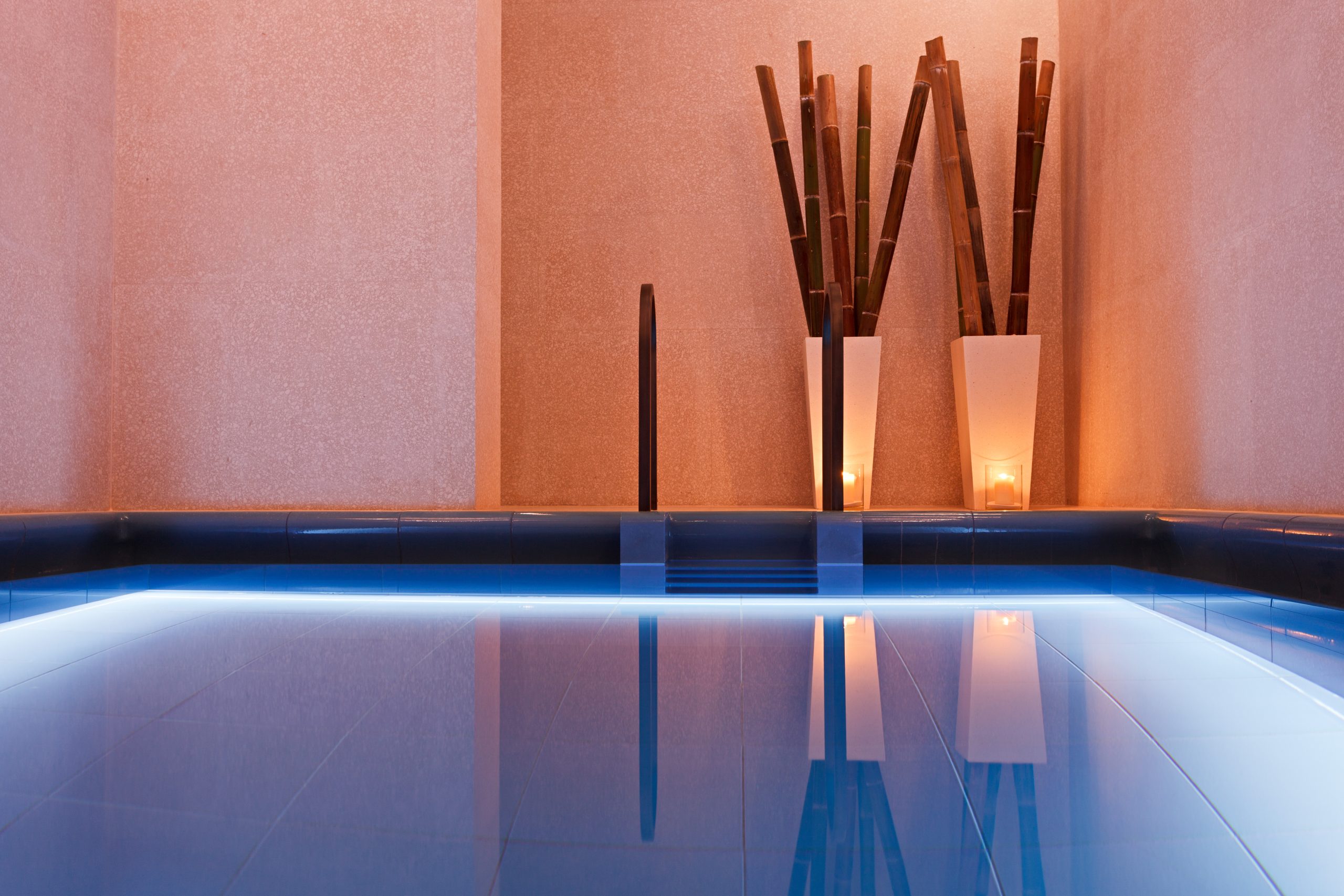 A closeup of a pool with lights and plants reflecting in the water.