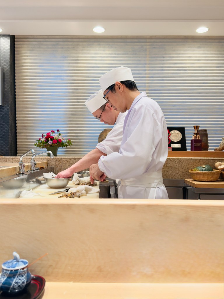 Two chefs working behind the counter at Tempura Kondo.