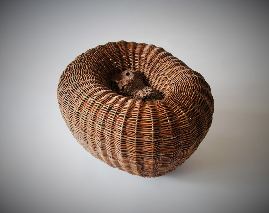 A woven basket sculpture with a stone in the middle.