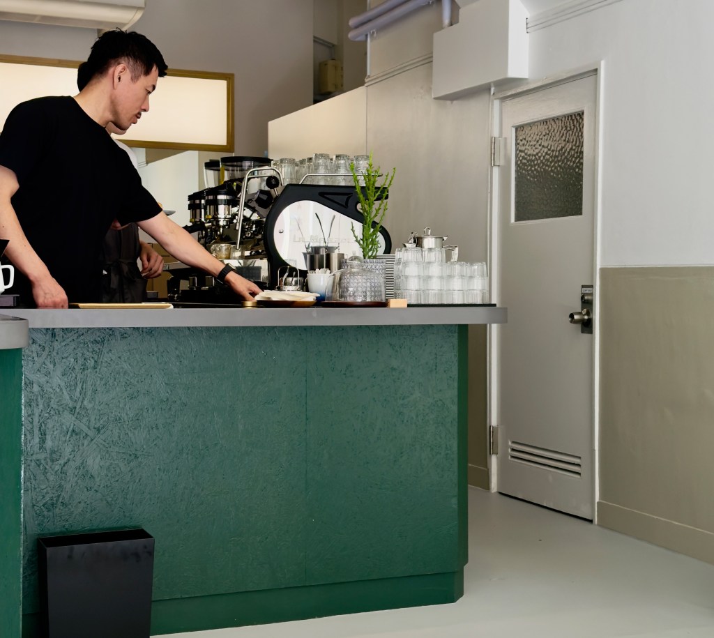 A barista at Nexpect Coffee working the counter.