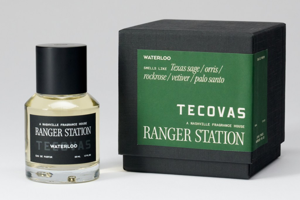 glass perfume bottle alongside black box with green label