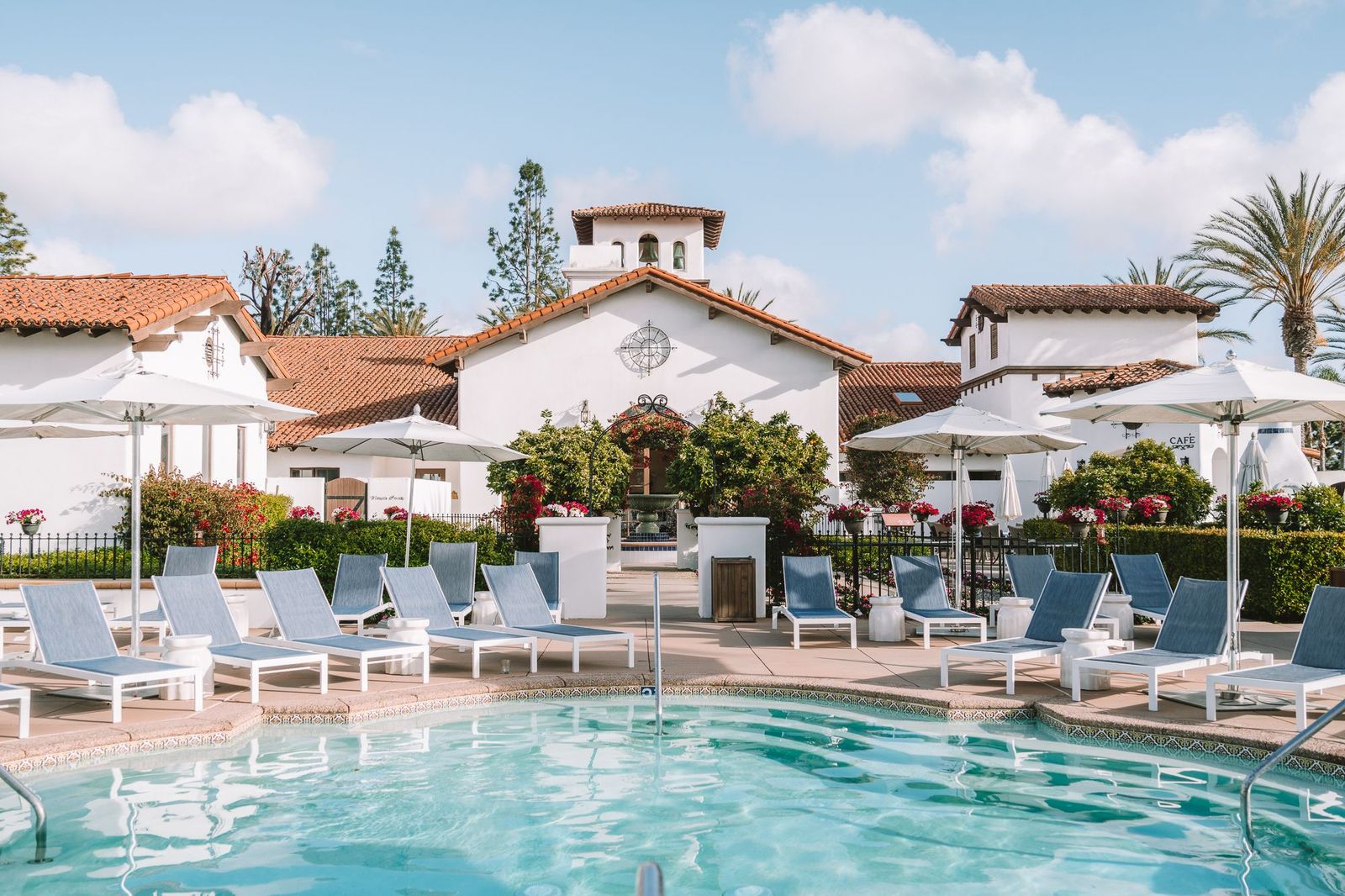 swimming pool and lounge chairs with a white building in the background