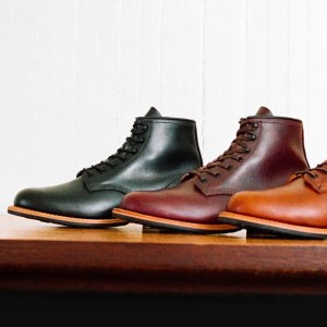 Red Wing Shoes' Beckman 6" boot, part of its heritage collection, is shown on a table with one shoe in Cigar, one in Black Cherry, and one in Black