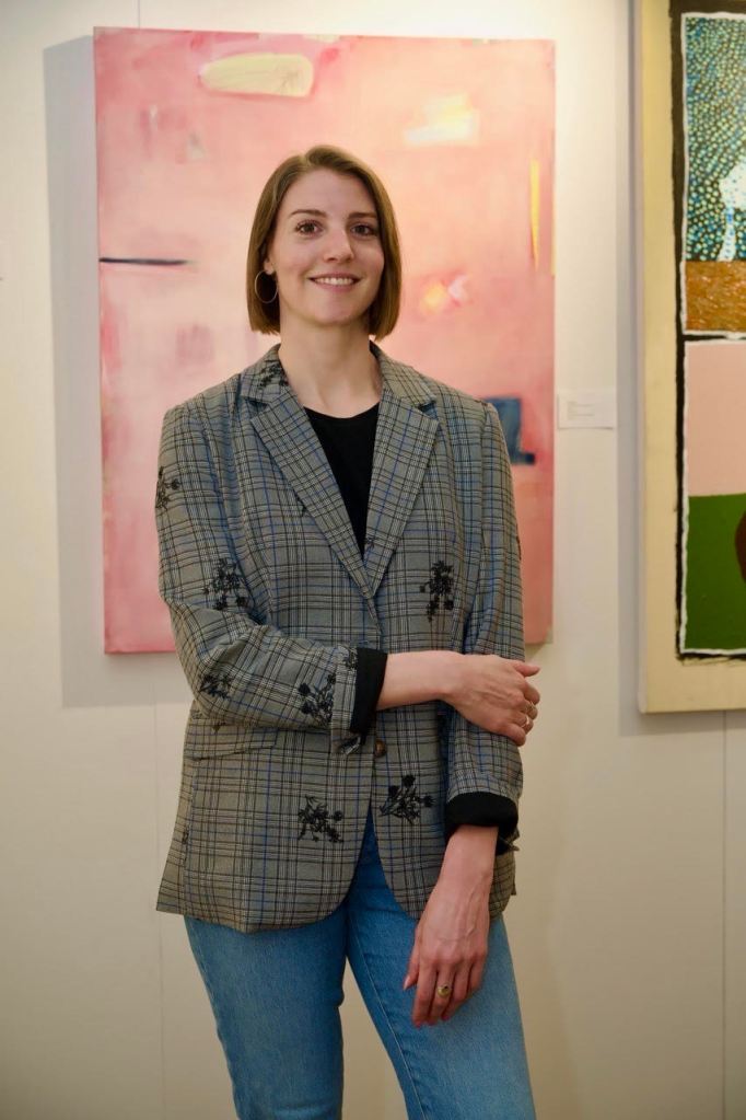 Erin Schuppert, Fair Director, standing in front of a pink painting.