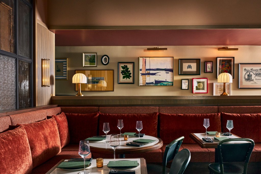 Small cocktail tables at Fidelity Hotel with framed vintage art and ephema on the wall.