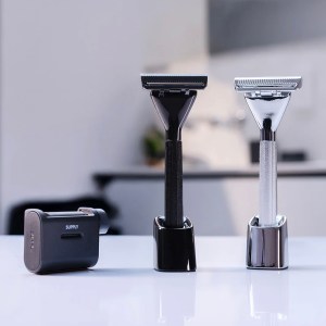 A black and a silver Single Edge Max razor sit in stands on a counter alongside a cartridge of razor blades