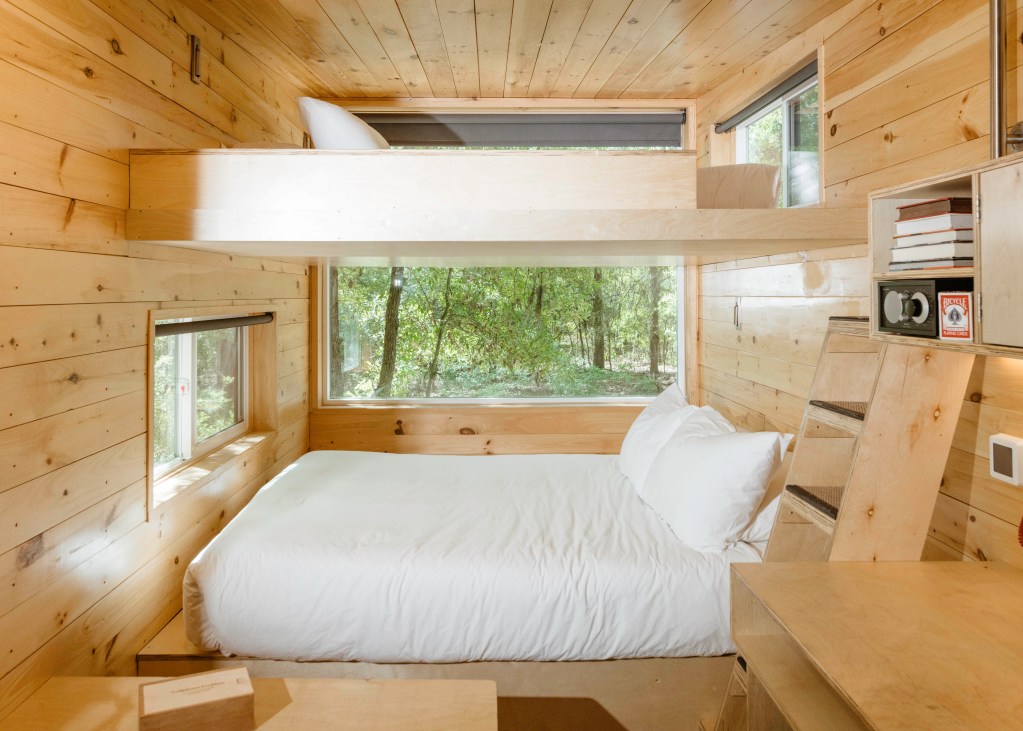 The interior of a Postcard Cabin in Shenandoah North with light wood and white bedding.