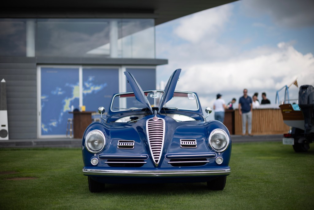 A front view of a blue car with top-opening doors at The Bridge IX.