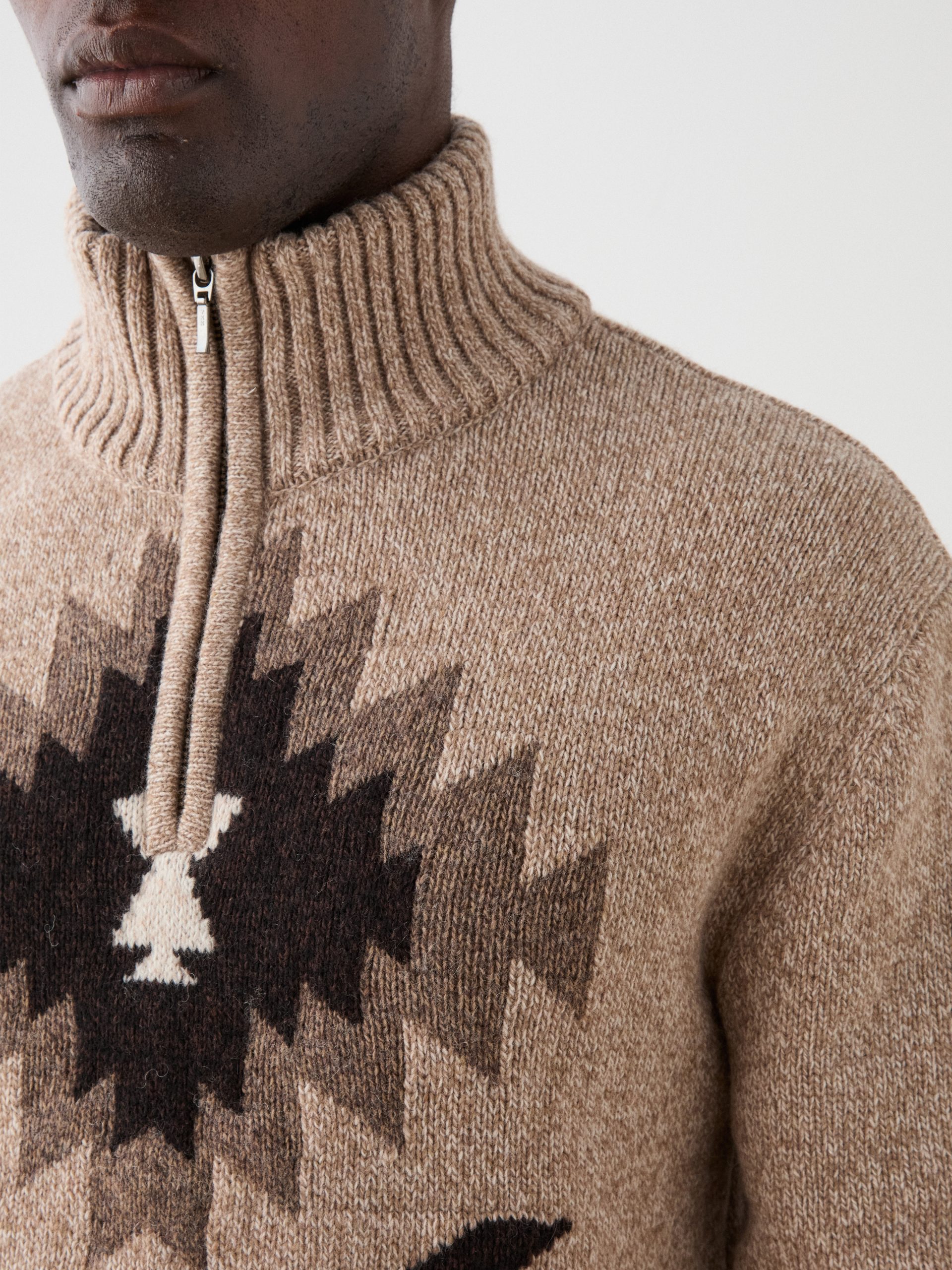 A shoulder detail of a model wearing a sweater with a graphic print on front.