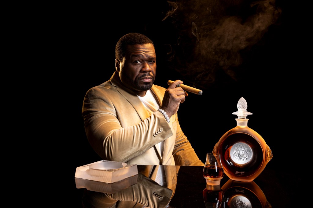 Curtis "50 Cent" Jackson smoking a cigar with his limited editor Lalique cognac bottle to his side.