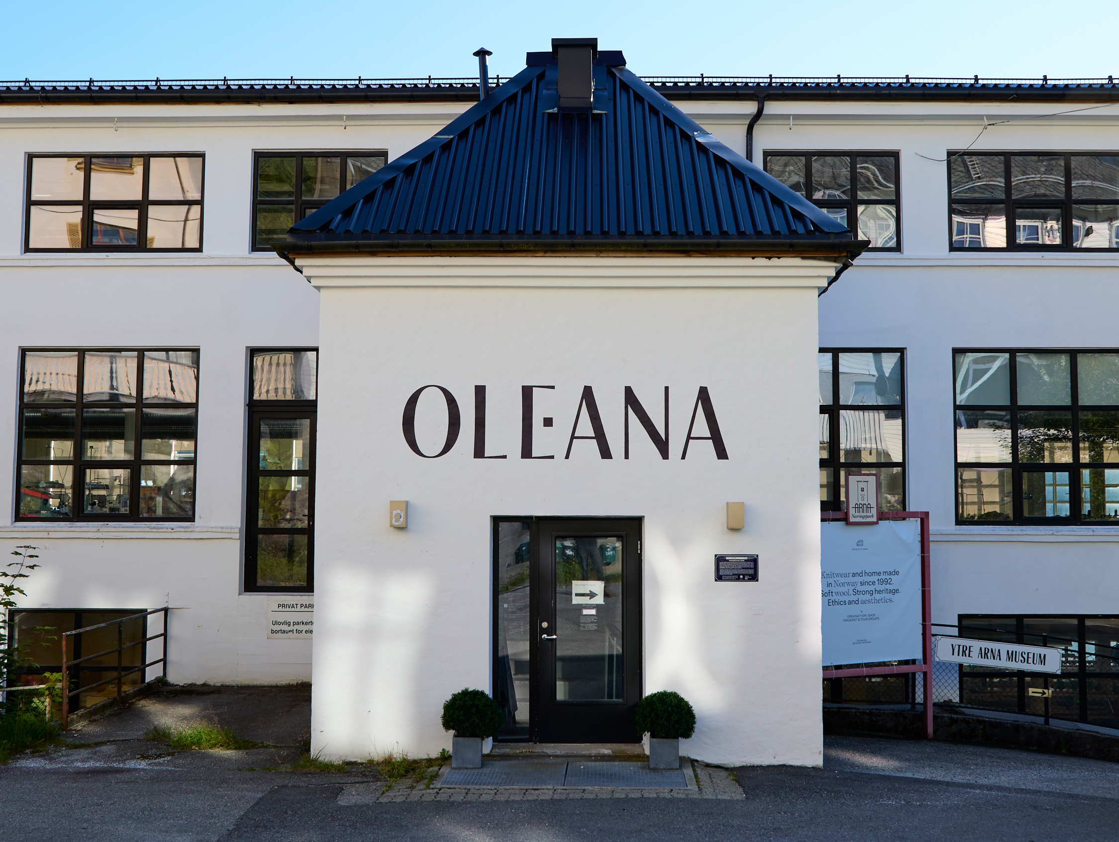 The front of a white factory building that says Oleana above the front door.