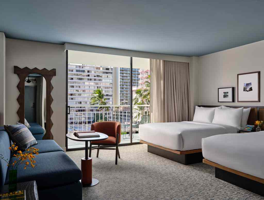 A double queen guest room at Romer House Waikiki with an outdoor deck.