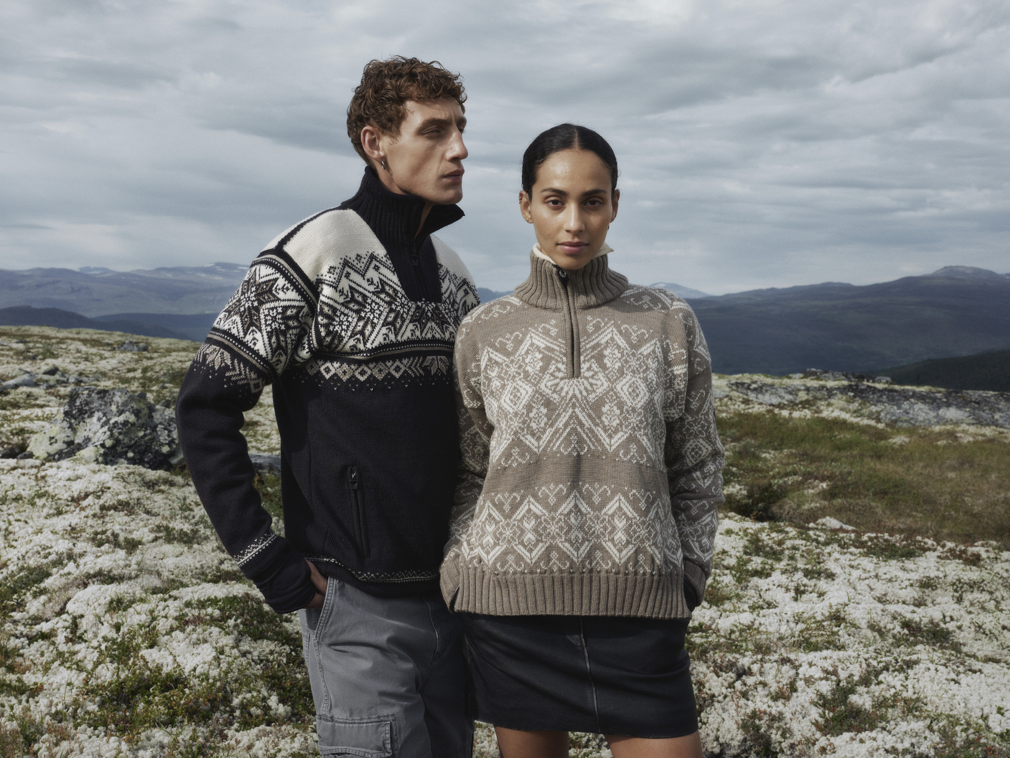 Two models wearing Dale of Norway sweaters with a mountain in the background.