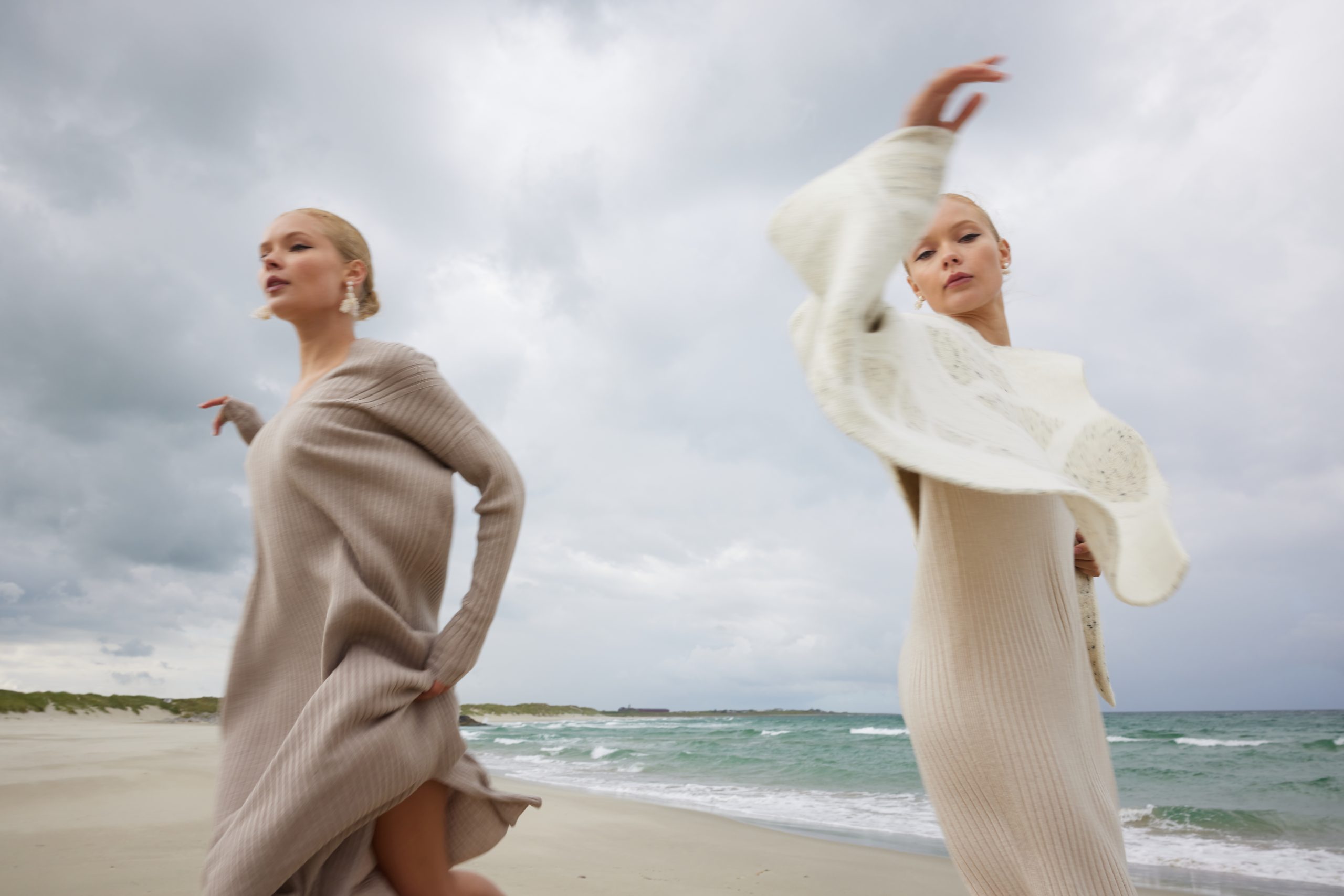 Two models dancing on the beach while wearing Woodling knits.