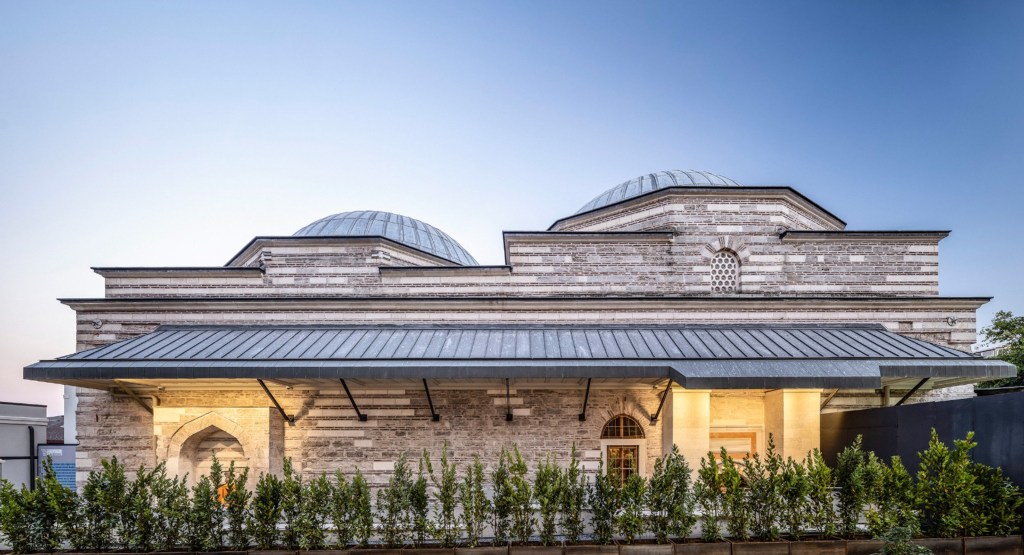An exterior view of the Zeyrek Cinili Hamam with domed roofs and surrounding landscaping.