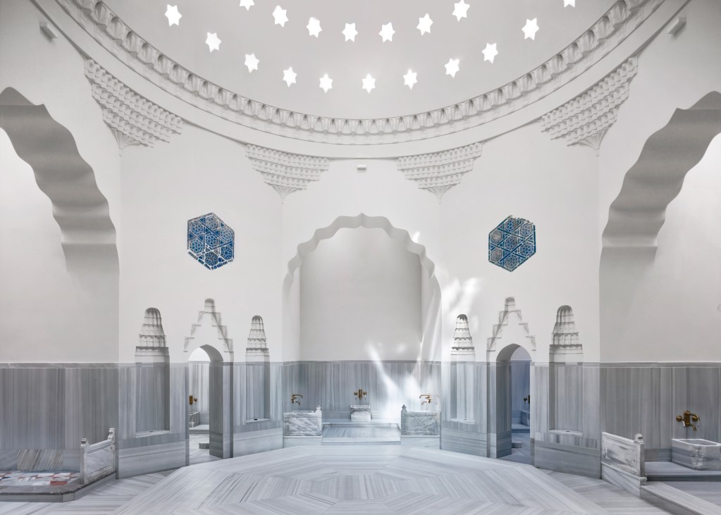 An interior view of the Zeyrek Cinili Hamam with domed ceiling and white and blue tiles.