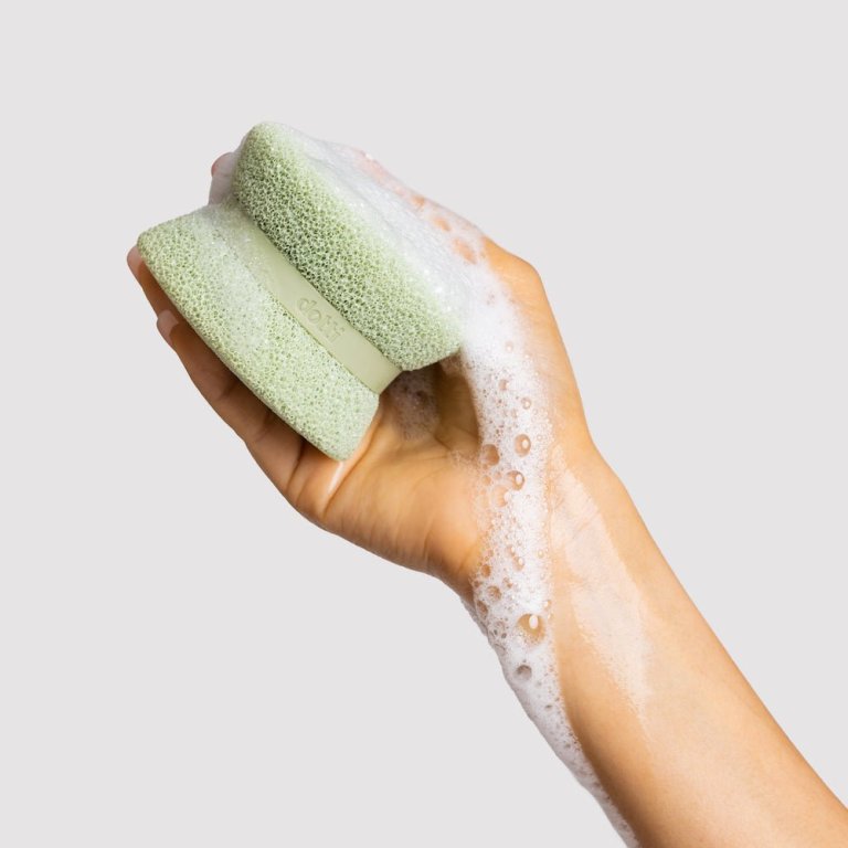 A hand holds a soapy sage Dotti Super Scrubber sponge