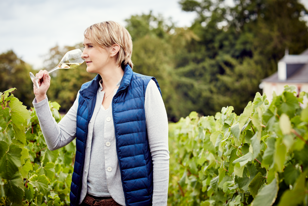 Julie Cavil sniffing a glass of Champagne in the vineyard.