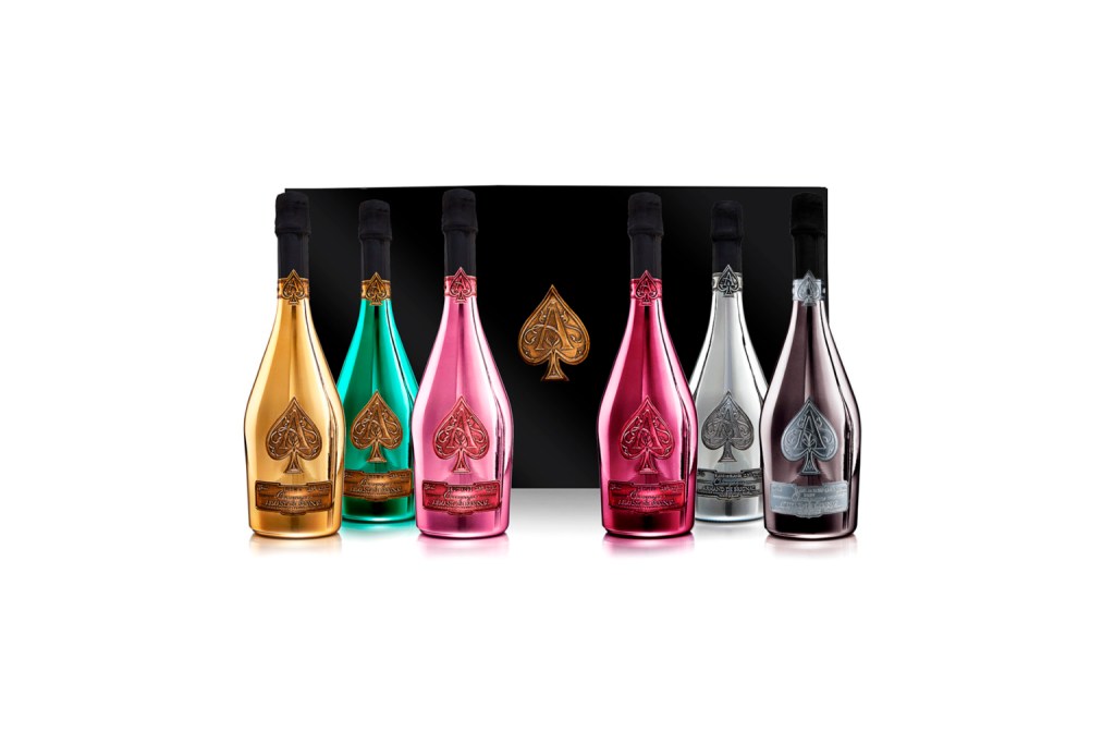 Armand de Brignac's La Collection bottles sitting in front of their black collector case on a white background.