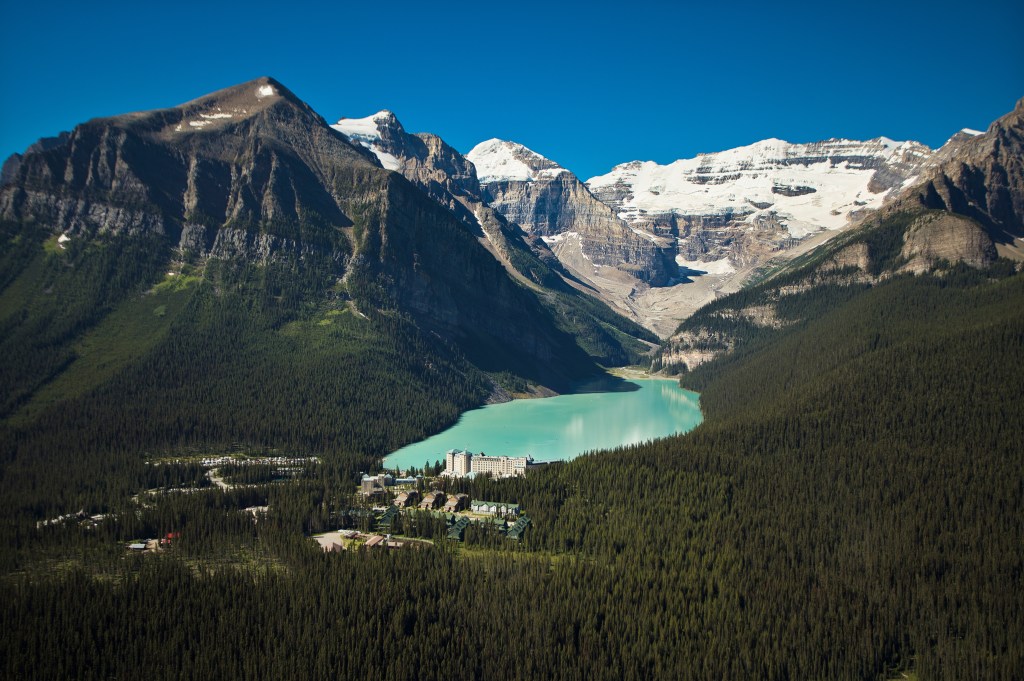 An aerial view of Fairmont Chateau Lake Louise and its surrounding mountainous landscape.